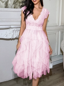Gros plan sur une robe en dentelle rose à col en V avec des couches de tulle étagées