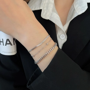 Detailed view of three-piece silver snake and curb chain bracelet set on female wrist