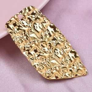 Close-up of golden irregular heart pendant with hammered texture on pink fabric