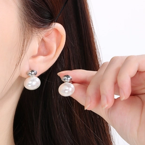 Elegant shell pearl earrings with silver bead studs shown on a model's ear lobe