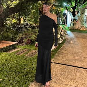 Detail of elegant black one-shoulder evening gown with mesh stitching and long sleeves