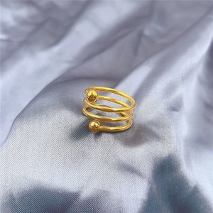 Close-up of a gold multi-layer coil ring with double beads on grey silk fabric