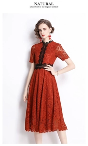 Detail of red floral lace dress featuring black crochet trim and intricate cutout texture