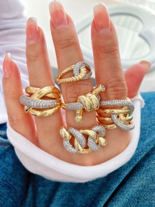 Detailed close-up of various gold-plated geometric rings with cubic zirconia pavé