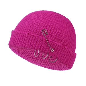 Close-up of ribbed knit beanie in hot pink with silver safety pin and metal rings