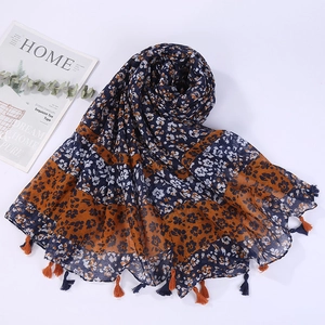 Detail of floral linen beach shawl with tassels in navy and orange brown tones
