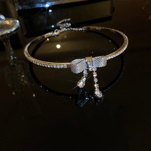 Detail shot of a silver bow choker necklace with sparkling rhinestones and tassels