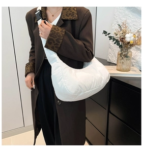 Detail of white quilted cloud bag featuring adjustable strap and black plastic buckle