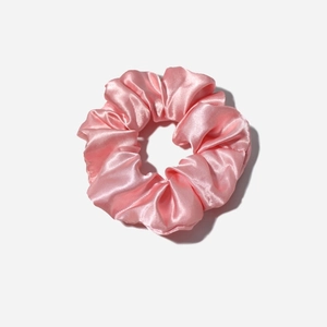 Close-up of pink satin scrunchie showing smooth silk texture and pleated design