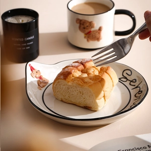 Detail of hand-painted puppy ceramic mug and plate set in a warm breakfast scene