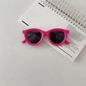 Close-up of pink children's sunglasses with black lenses on a white notebook background