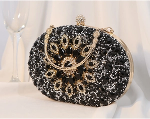 Elegantes Detail des schwarzen Kristallblumenmusters auf goldfarbener Abendhandtasche