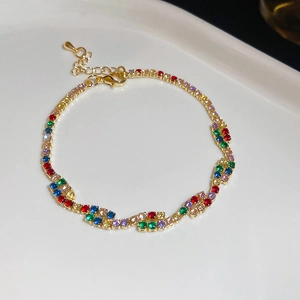 Gold plated bracelet with wavy links and colorful zircon gemstones on a white tray