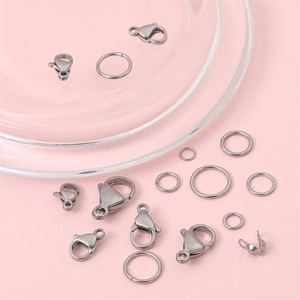 Stainless steel jewelry kits with lobster clasps and jump rings on a glass tray