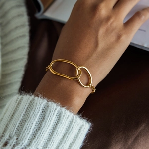 Close-up of a gold interlocked double-ring chain bracelet on a model wrist