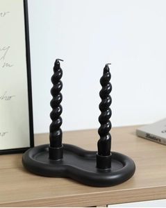 Detail view of a black ceramic cloud candle holder with two spiral taper candles on wood
