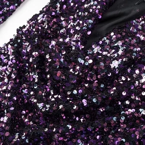 Detail shot of shimmering purple sequins on a long-sleeve luxury party cocktail dress