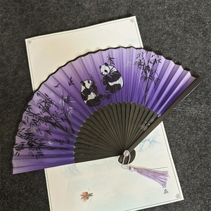 Macro detail of a purple hand fan featuring painted pandas, bamboo and a silk tassel