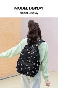 Back view of a black student backpack with white daisy floral patterns on a girl model