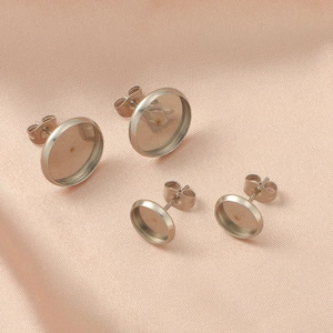 DIY stainless steel stud earring bases in two sizes on pink textured background