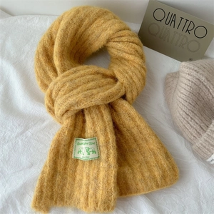 Close-up of ginger yellow chunky knit wool scarf featuring a vintage woven brand label