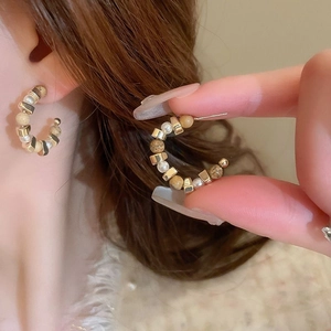 Gros plan de boucles d'oreilles créoles en C avec perles et marbre au style vintage français