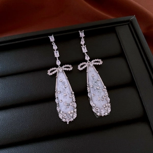 Detail of silver bowknot earrings with zircon teardrop pendants on jewelry tray