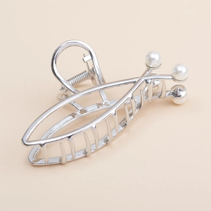 Elegant silver hollow metal hair claw clip with four white pearls on a beige background