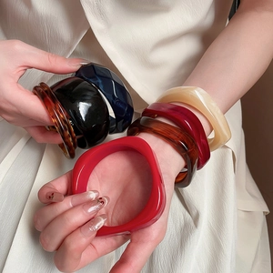 Close-up of stacked acrylic leopard print bangles in diverse colors on model wrist