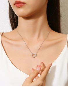 Close-up of a silver heart-shaped necklace with crystals worn on a woman's neck