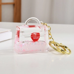 Macro detail of mini clear bag keychain with pink quicksand and red love heart