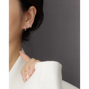 Close-up of a minimalist silver beaded hoop earring worn by a model in a studio setting