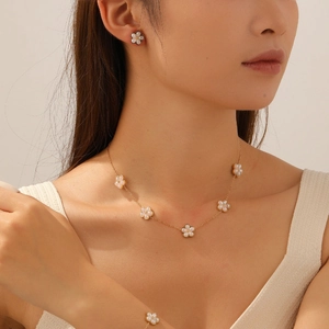 Detailed view of elegant gold necklace, earrings and bracelet set with white flower charms