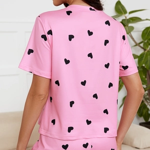 Short-sleeved pink pajama top with black heart prints for women in a cozy home setting
