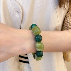 Détail d'un bracelet en perles d'acrylique vertes aux textures irrégulières au poignet
