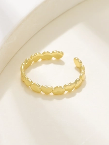 Dettaglio dell'anello a cuore dorato regolabile con design minimalista su un vassoio