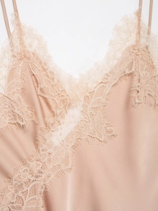Close-up of champagne satin fabric with delicate white eyelash lace on the V-neckline