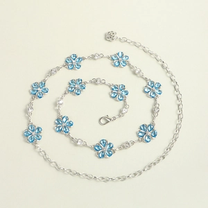 Close-up of silver metal waist chain featuring blue flower charms and clear rhinestones