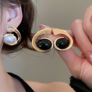 Close-up of gold metal tassel earrings with black and white oval gemstones