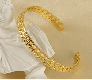 Gros plan détaillé du bracelet gourmette doré évidé sur fond de soie élégante