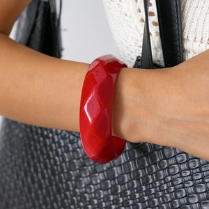 Close-up of a bold red faceted resin bangle featuring chunky geometric wave-like texture