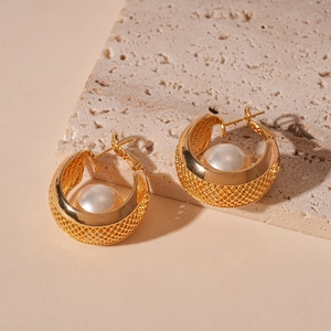 Detail of gold wide C-shaped hoop earrings with mesh texture and inlaid pearl