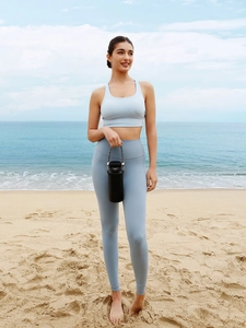 Outdoor shot of a woman in light blue yoga set with sports bra and leggings on the beach