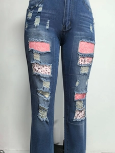 Dettaglio di jeans blu strappati con paillettes rosa e stampa leopardata negli strappi
