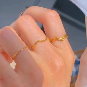 Three-piece stackable gold wave ring set with micro-diamond accent on female hand