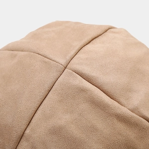 Macro detail of camel faux suede fabric texture and reinforced cross stitching on the cap