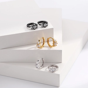 Detailed view of silver, gold, and black cubic zirconia hoop earrings on stone