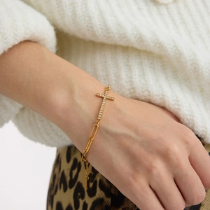 Gouden paperclip armband met schitterende strass kruishanger om de pols gedragen
