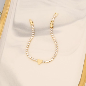 Macro shot of gold heart zircon tennis bracelet with polished 18K gold finish on a tray