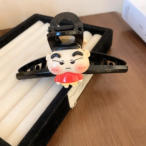Detail shot of a glossy black hair claw clip featuring a cute cartoon character ornament